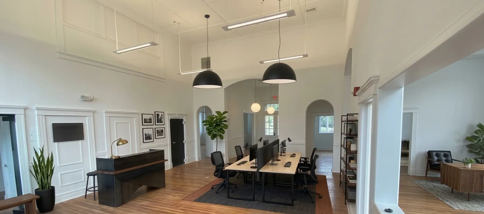 Suite 305 open office in the Company Store building: heart-pine floors, tall ceilings, black pendant lights and arched doorways